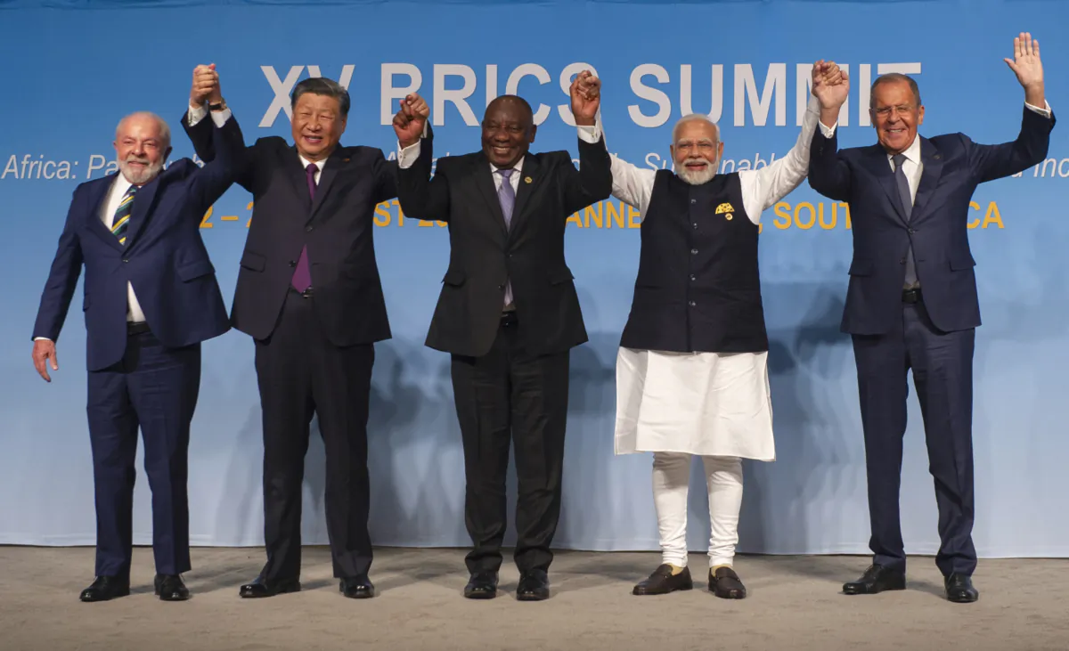 (L to R): Brazil's President Luiz Inacio Lula da Silva, China's leader Xi Jinping, South African President Cyril Ramaphosa, Indian Prime Minister Narendra Modi, and Russia's Foreign Minister Sergei Lavrov raise their arms as they pose for a group photograph at the BRICS Summit in Johannesburg, South Africa, on Aug. 23, 2023. (Alet Pretorius/Pool/AFP via Getty Images)