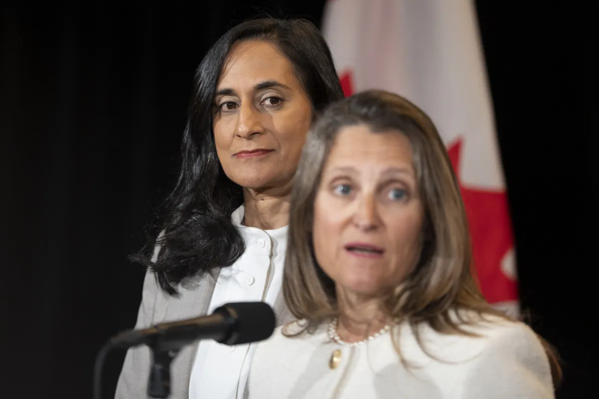 President of the Treasury Board Anita Anand, left, looks on as Deputy Prime Minister and Minister of Finance Chrystia Freeland speaks to reporters during the Liberal Cabinet retreat in Charlottetown on Aug. 22, 2023. (Darren Calabrese/The Canadian Press)
