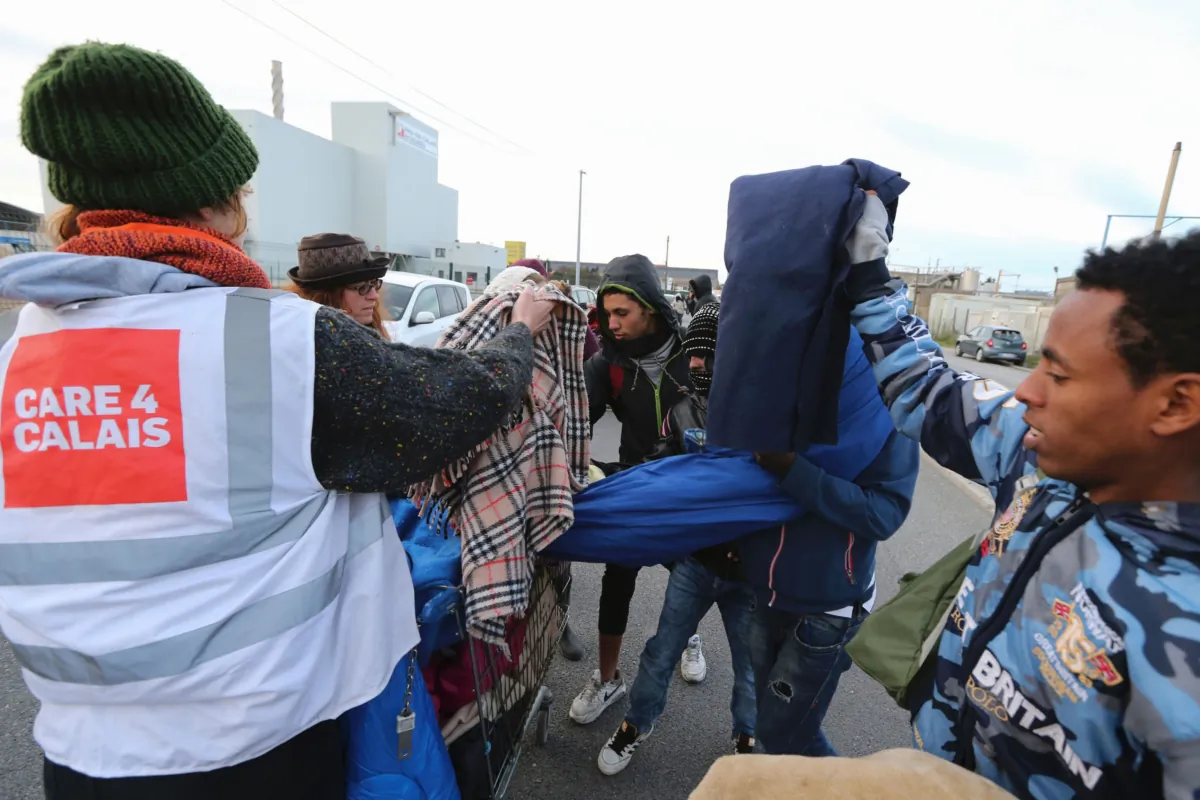 Volunteers of UK registered charity Care4Calais distribute blankets to migrants near the "Jungle" migrant camp in Calais, northern France, on Oct. 27, 2016. (Francois Nascimbeni/AFP via Getty Images)