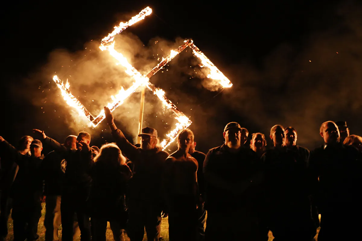 Members of the National Socialist Movement, one of the largest neo-Nazi groups in the US, hold a swastika burning after a rally in Draketown, Georgia, on April 21, 2018. (Spencer Platt/Getty Images)
