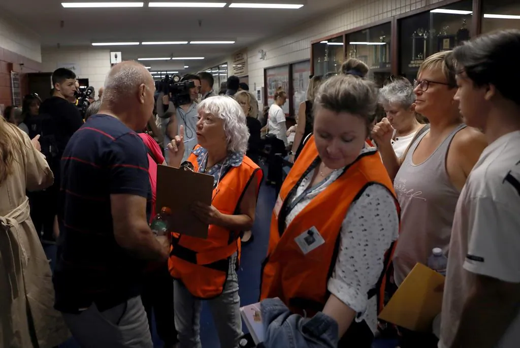 An Emergency Social Services representative speaks with an evacuee at a reception centre for those evacuated due to the McDougall Creek wildfire in West Kelowna, B.C., on Aug. 22, 2023. (The Canadian Press/Chad Hipolito)
