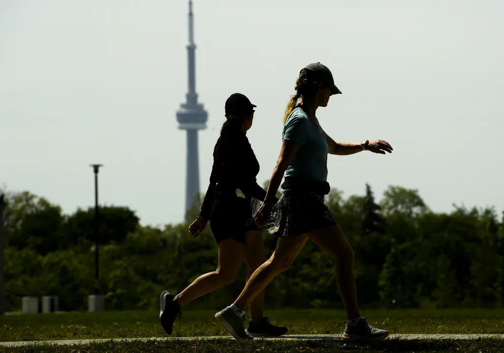 The CN tower is seen behind people exercising in Toronto on June 2, 2021. Canadians' freedoms are increasing but remain below pre-pandemic levels, says a new report. (Nathan Denette/The Canadian Press)