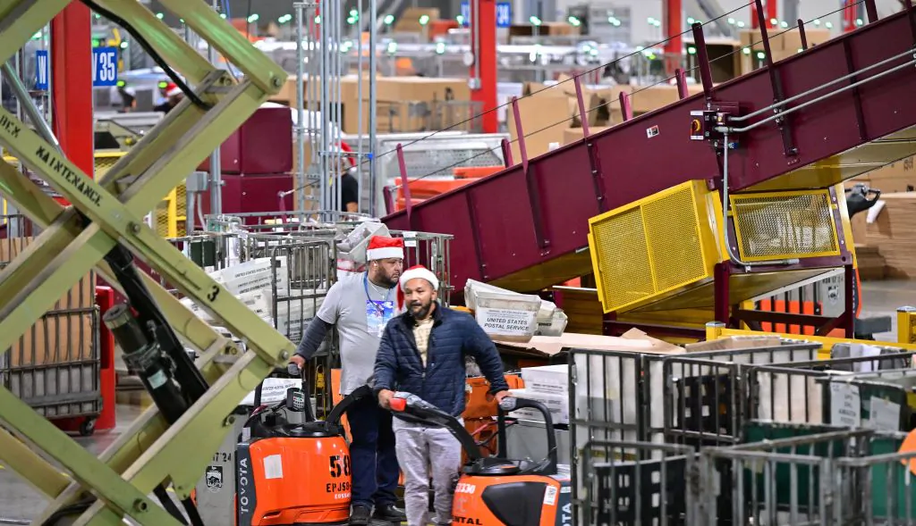 US Postal Service employees, some wearing Santa hats, sort mail at the Los Angeles Processing and Distribution Center in preparation for another busy holiday season in Los Angeles on Nov. 30, 2022. The center operates 24 hours a day, 365 days a year in a warehouse the size of 22 football fields. (Frederic J. Brown/AFP via Getty Images)