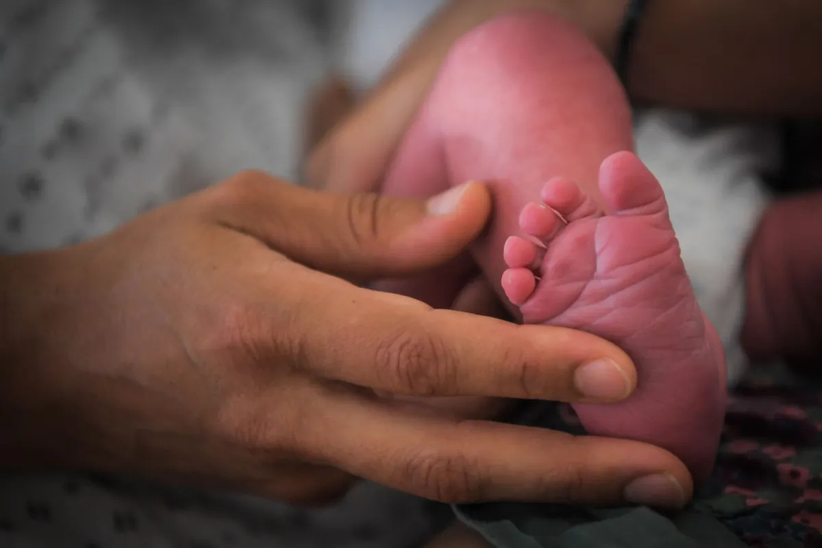 A woman holds the foot of a baby in a file photo. (Loic Venance/AFP via Getty Images)