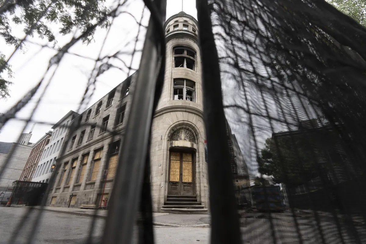 The site of a fire in Old Montreal that killed seven people sits behind fencing on Aug. 3, 2023. (The Canadian Press/Christinne Muschi)