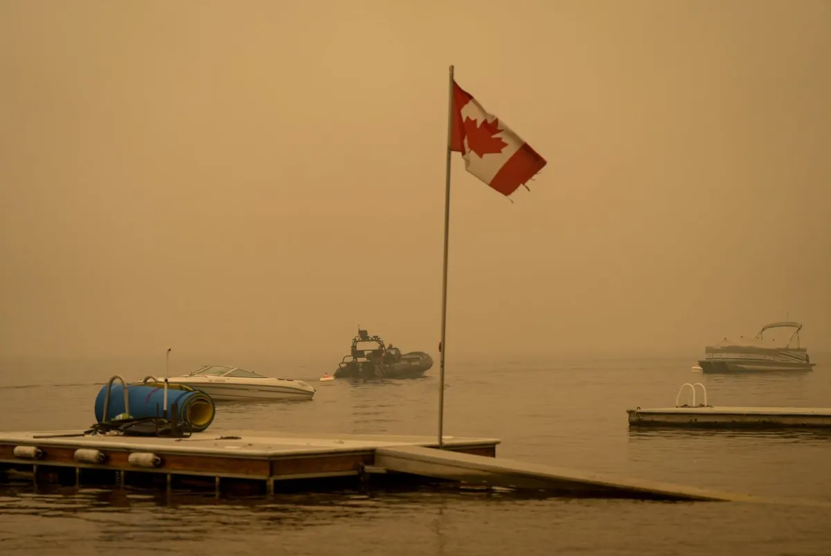 Thick smoke from wildfires fills the air as RCMP officers on a boat patrol Shuswap Lake, in Scotch Creek, B.C., on , Aug. 20, 2023. (The Canadian Press/Darryl Dyck)