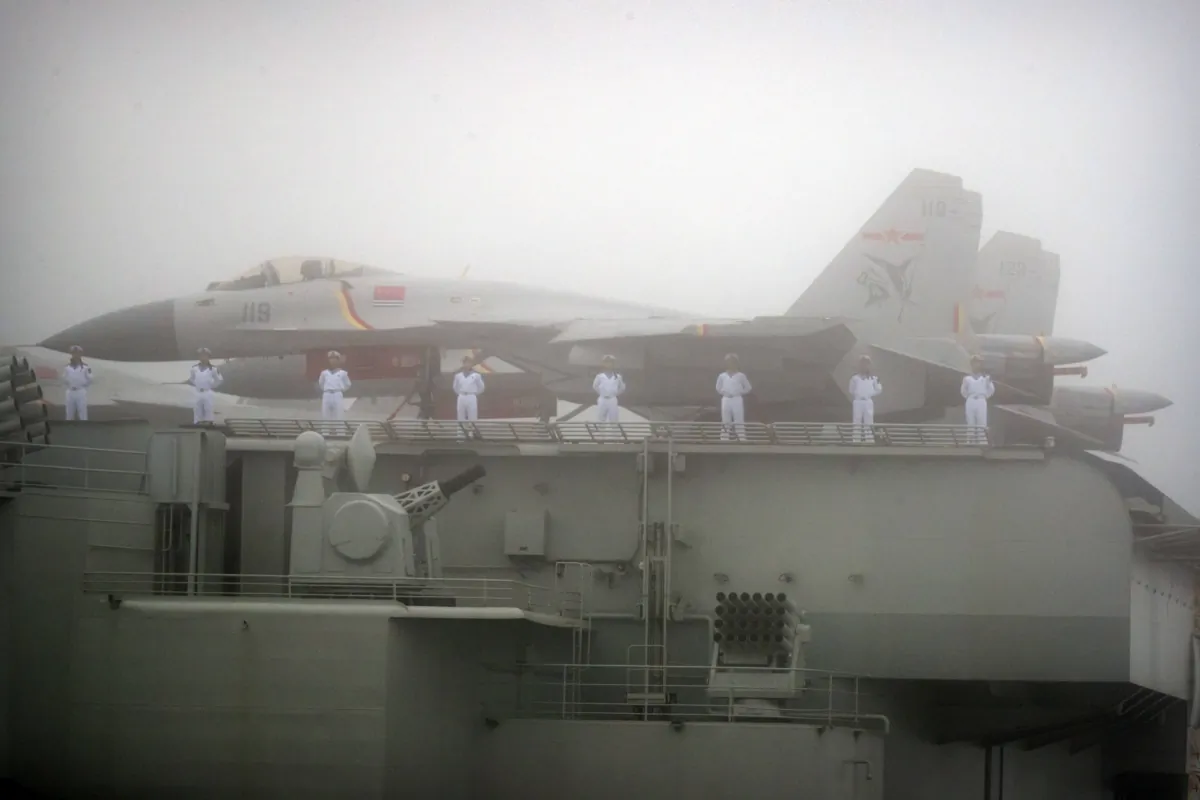 Sailors stand near fighter jets on the deck of the Chinese People's Liberation Army (PLA) Navy aircraft carrier Liaoning as it participates in a naval parade to commemorate the 70th anniversary of the founding of China's PLA Navy in the sea near Qingdao, in eastern China's Shandong Province, on April 23, 2019. (Mark Schiefelbein/AFP via Getty Images)