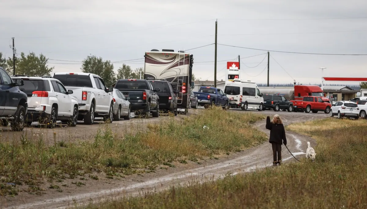 Vehicles line up for fuel at Fort Providence, N.W.T., on the only road south from Yellowknife, on Aug. 17, 2023. (The Canadian Press/Jeff McIntosh)
