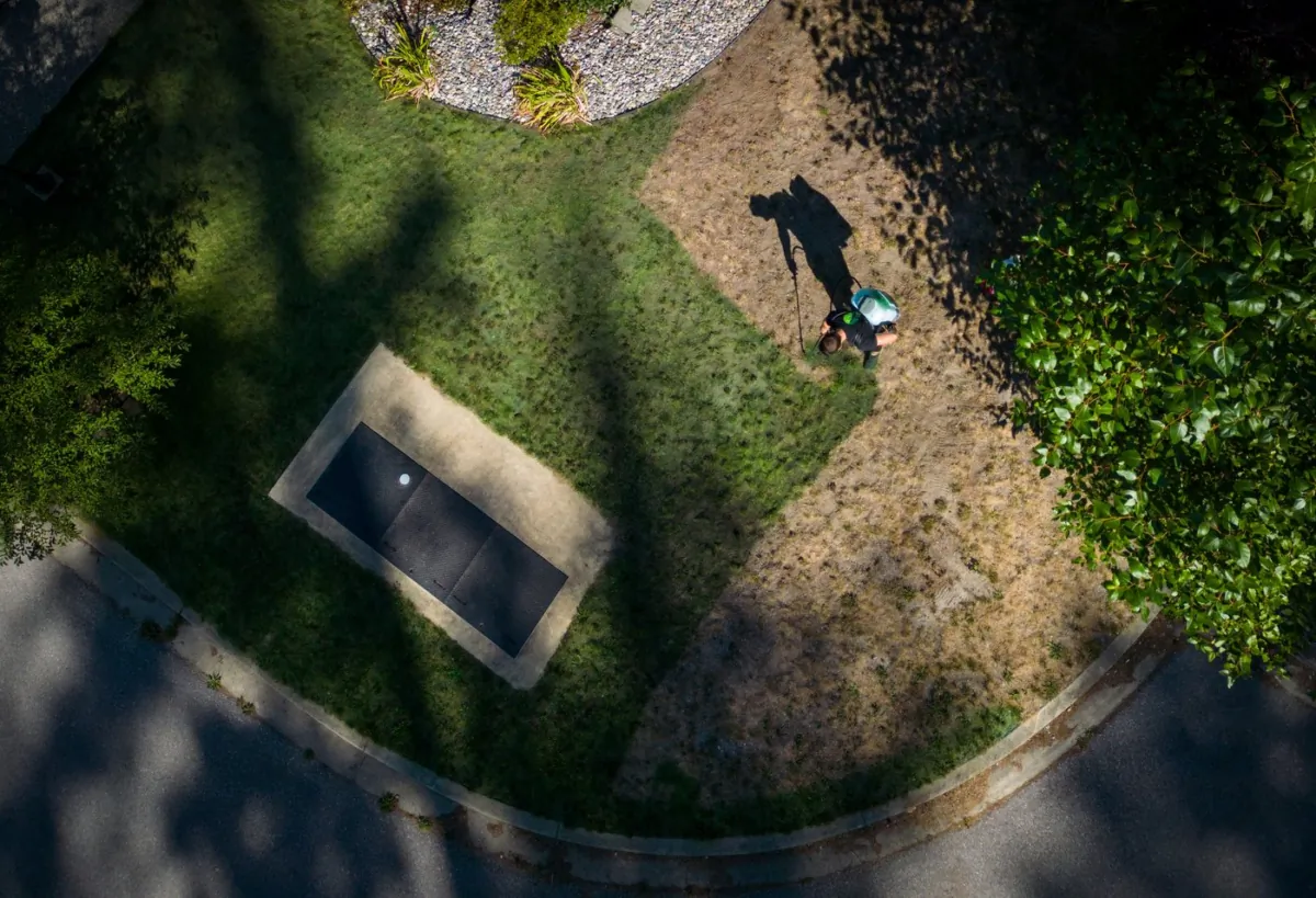 Tyler Basham paints the grass outside a house in Maple Ridge, B.C. on Aug. 17, 2023. (The Canadian Press/Darryl Dyck)