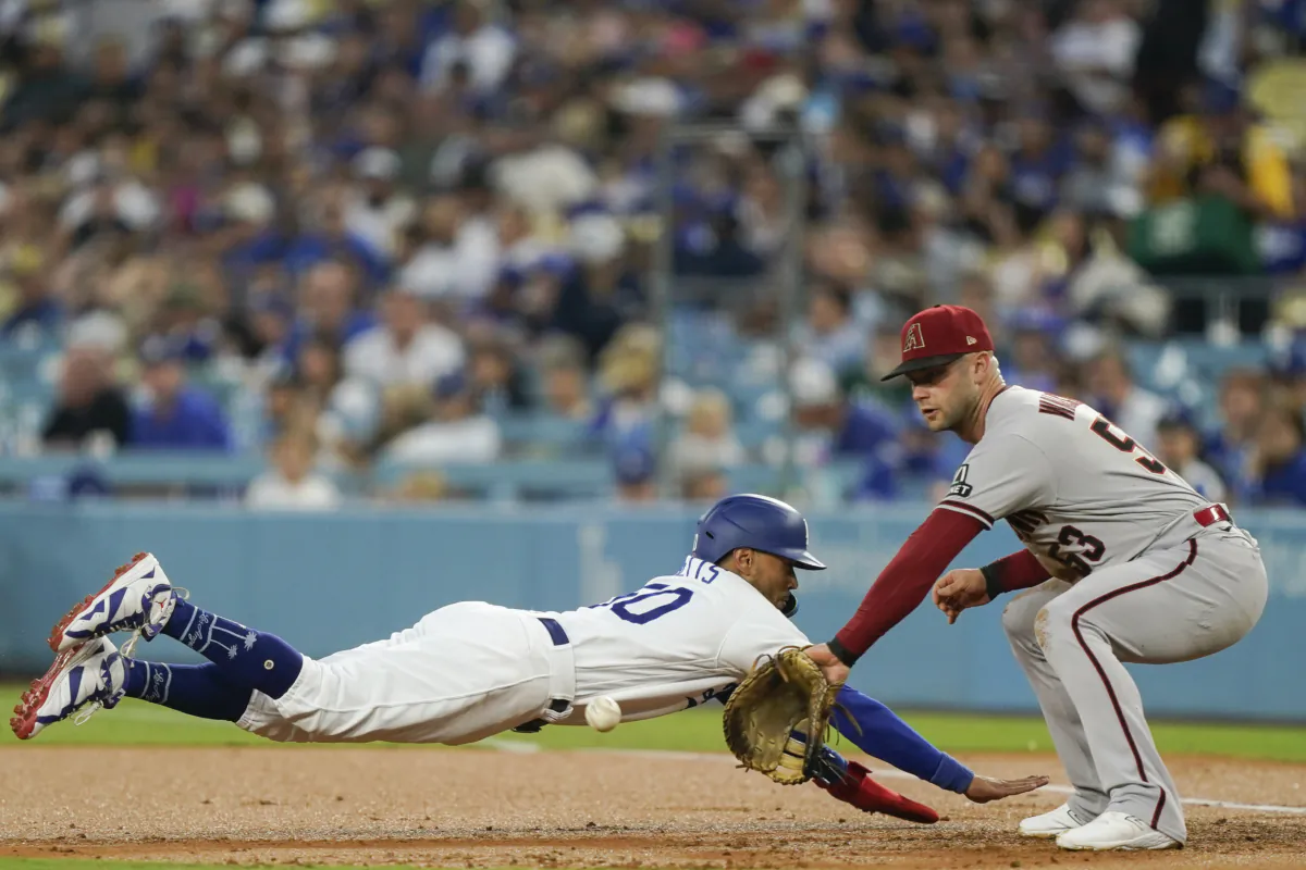 Los Angeles Dodgers' Mookie Betts, left, dives back to first on a pickoff attempt as Arizona Diamondbacks first baseman Christian Walker waits for the throw during the first inning of a baseball game in Los Angeles on Aug. 29, 2023. (Ryan Sun/AP Photo)