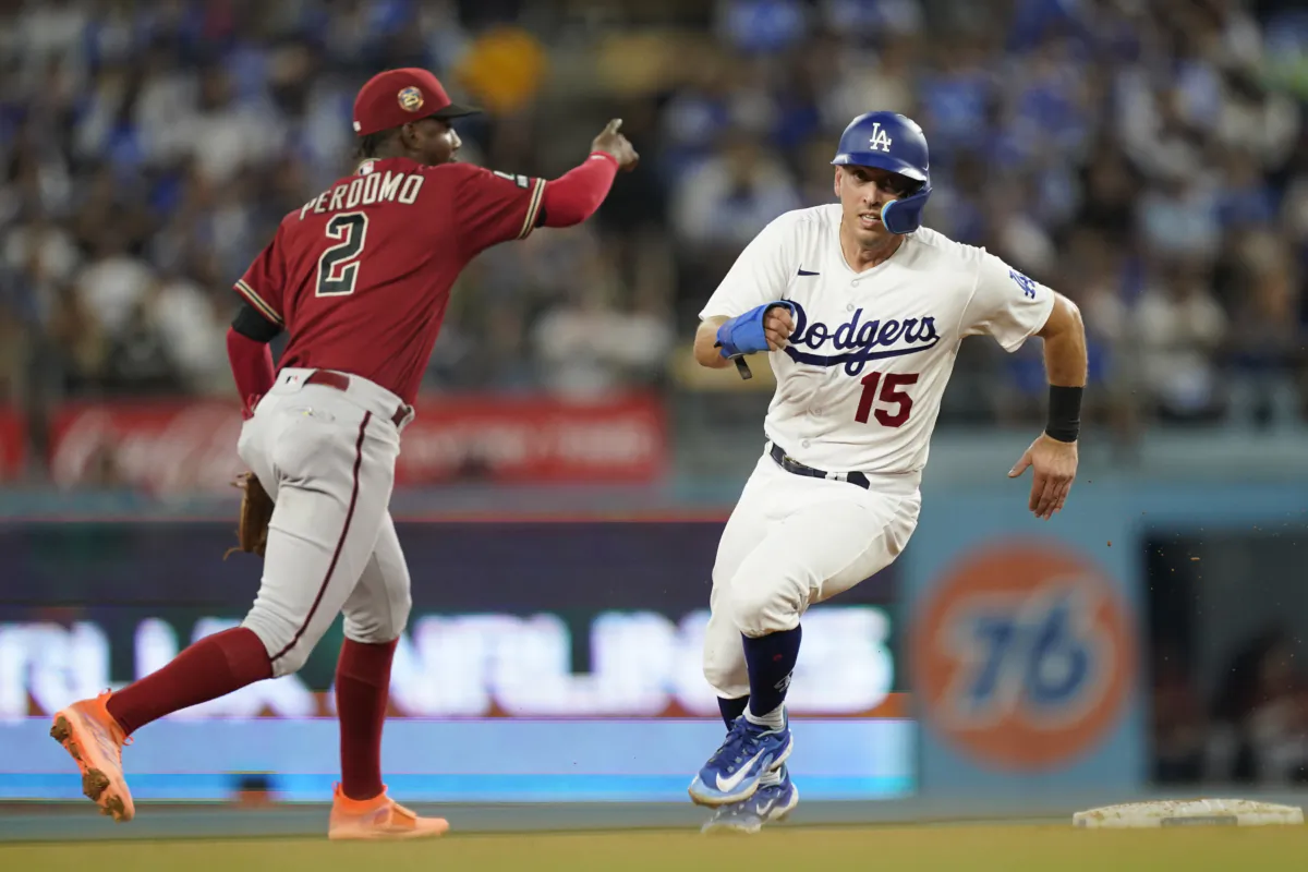 Los Angeles Dodgers' Austin Barnes (15) runs past Arizona Diamondbacks shortstop Geraldo Perdomo (2), advancing to third on a double by Freddie Freeman during the fourth inning of a baseball game in Los Angeles on Aug. 30, 2023. (AP Photo/Ryan Sun)