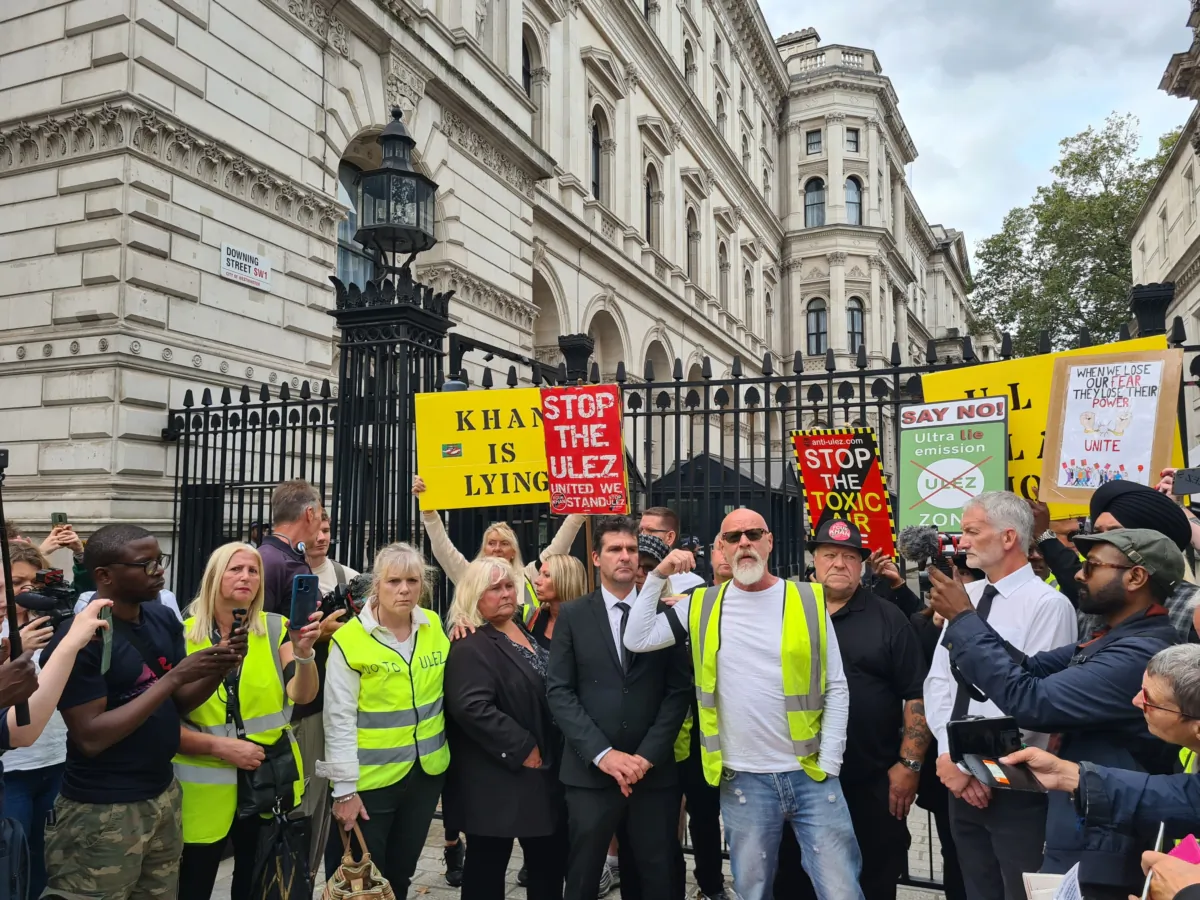 A photo of protesters, taken outside Downing Street, on Whitehall, London, displays signage criticising the mayor of London, Sadiq Khan, and the ULEZ expansion on Aug. 29, 2023. (Joseph Robertson / The Epoch Times)