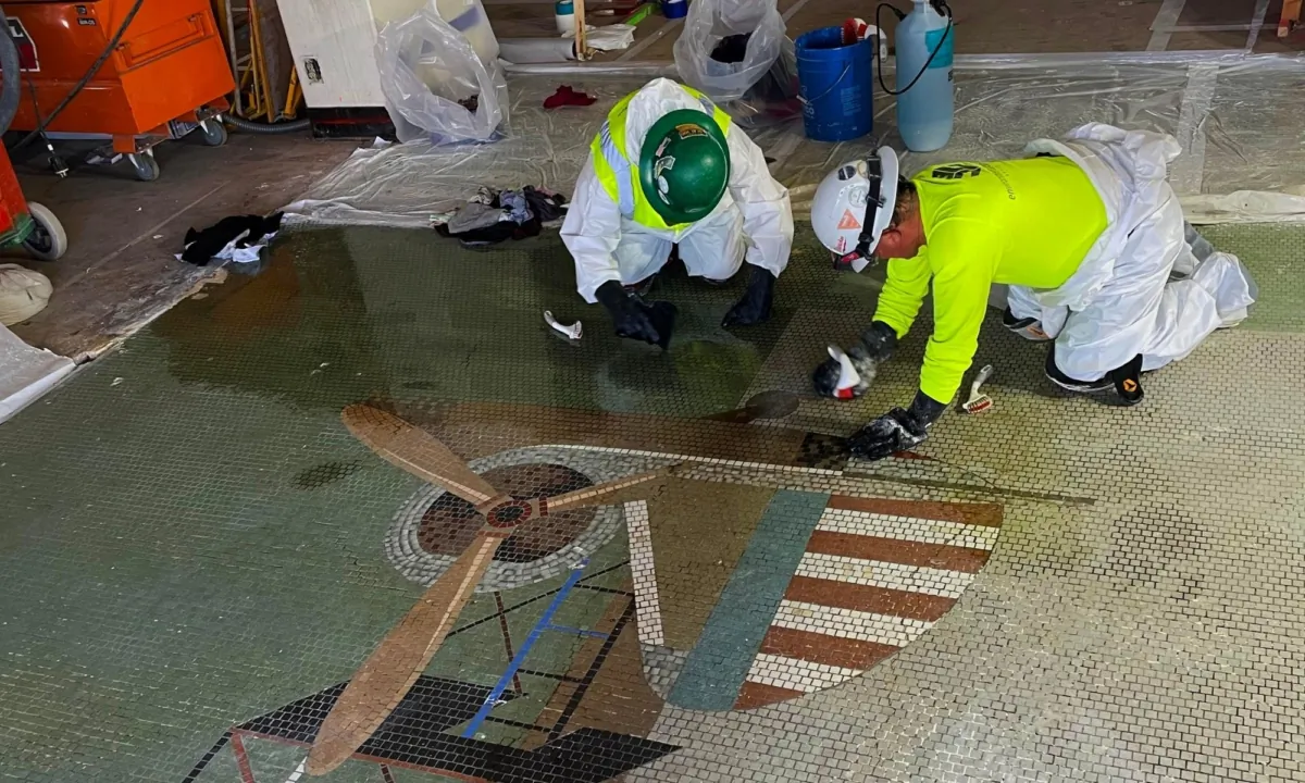 Workers unveil mosaic vignette of propeller airplane in artwork by artist Grace Clements in Long Beach Airport's Historic Terminal. (Courtesy of the City of Long Beach)