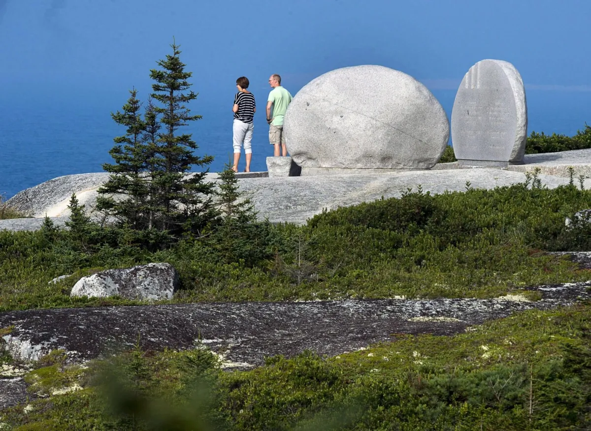 Visitors look out to the ocean from the Swissair Flight 111 memorial at Whalesback near Peggy's Cove, N.S. on Aug. 30, 2018. (The Canadian Press/Andrew Vaughan)