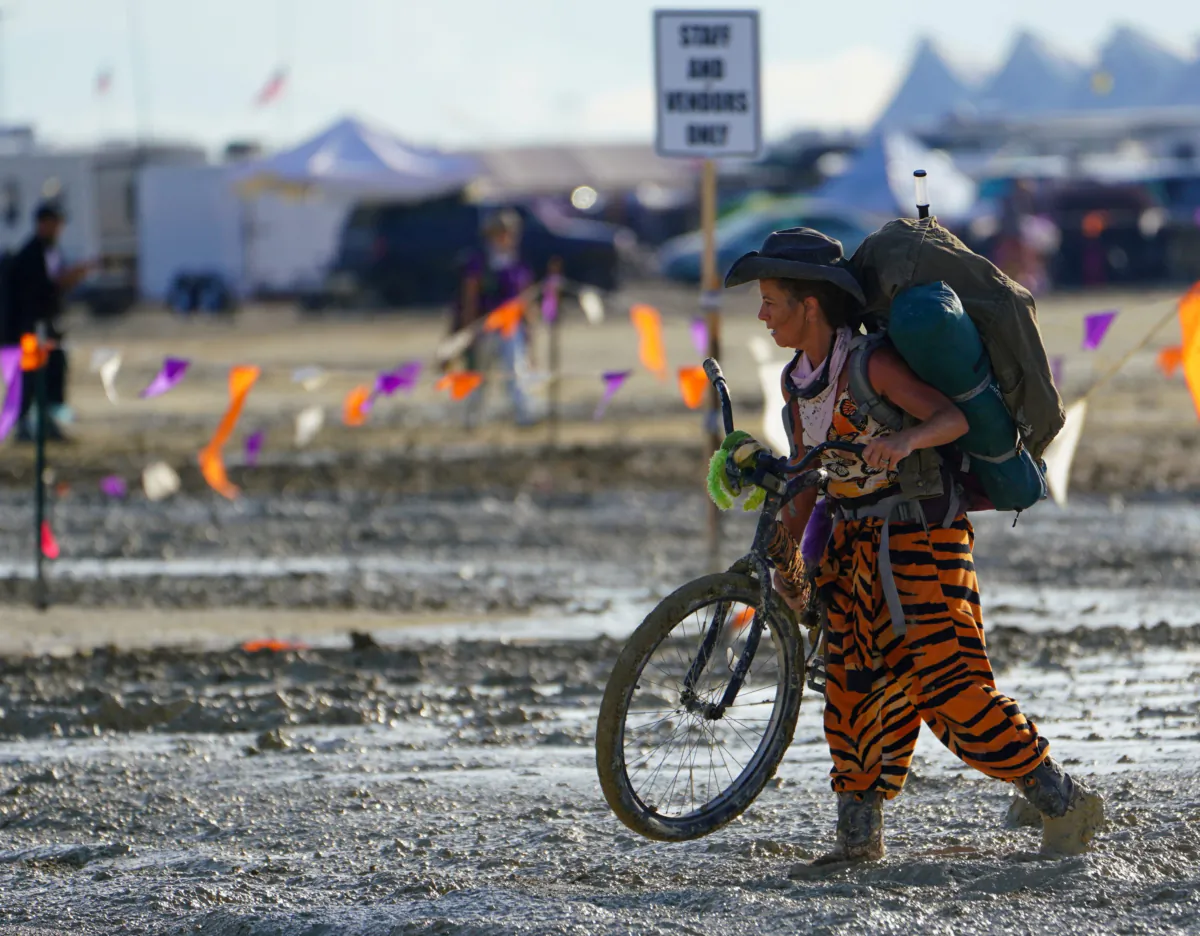 A Burning Man participant walks their bike through the mud near the exit, after a severe rainstorm left tens of thousands of revelers attending the annual festival stranded in mud in Black Rock City, in the Nevada desert on Sept. 3, 2023. (Trevor Hughes/USA Today Network via Reuters)