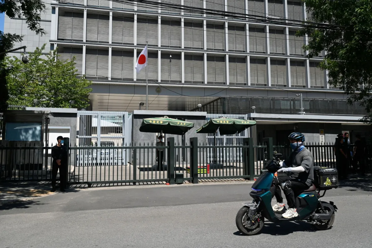 A man rides his motorcycle past the entrance of the Japanese embassy in Beijing on Aug. 29, 2023. (Pedro Pardo/AFP via Getty Images)
