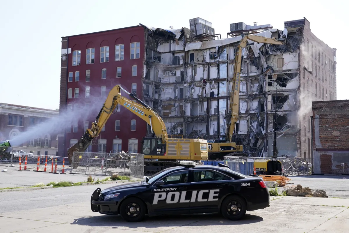 A police officer sits parked at the site of a building collapse at the start of demolition in Davenport, Iowa, on June 12, 2023. (Charlie Neibergall/AP Photo)