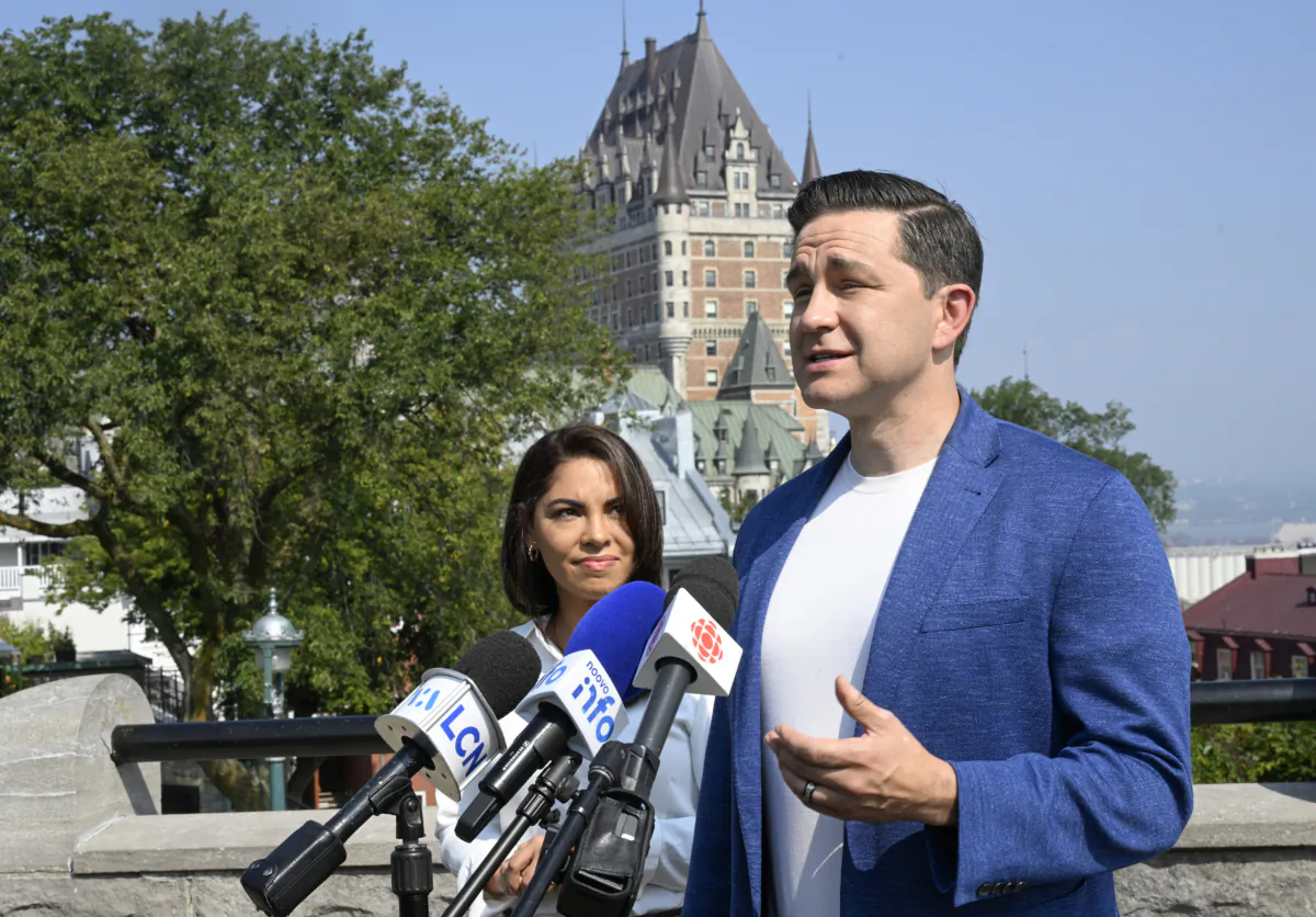 Conservative Leader Pierre Poilievre speaks duringa news conference as his wife Anaida looks on, in Quebec City on Sept. 6, 2023. (Jacques Boissinot/The Canadian Press)