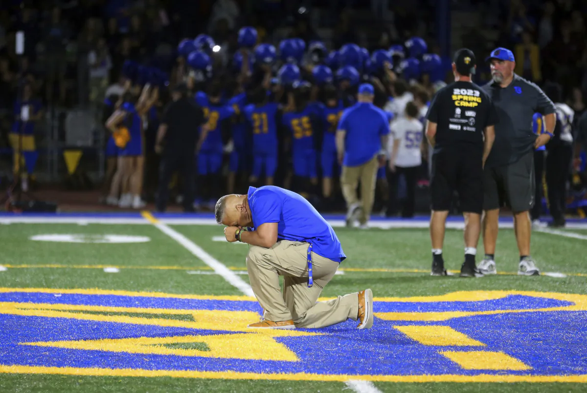Bremerton High School assistant coach Joe Kennedy takes a knee and prays at the 50-yard line after Bremerton's win over Mount Douglas in a high school football game at Bremerton Memorial Stadium in Bremerton, Wash., on Sept. 1, 2023. (Meegan M. Reid/Kitsap Sun via AP)