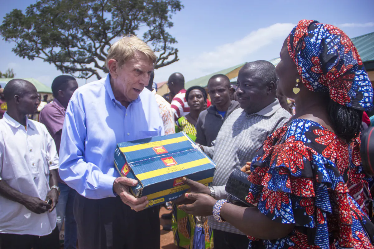 William Murray presents a carton of spaghetti to a widow in Mangu, Nigeria, on Sept. 1, 2023. (Masara KIm)
