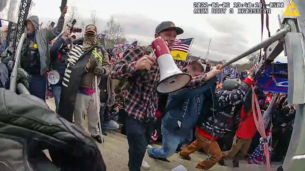 Sean Michael McHugh of Auburn, Calif., holding a bullhorn, helps push a framed Donald Trump banner into the police line at the U.S. Capitol on Jan. 6, 2021. (Metropolitan Police Department/Screenshot via The Epoch Times)