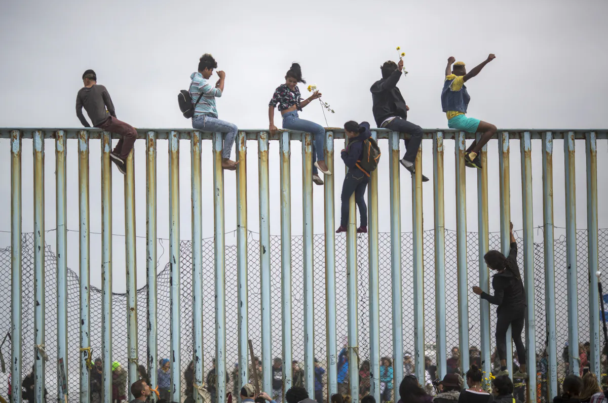 Illegal immigrants climb a section of the U.S.–Mexico border fence in Tijuana, Mexico, on April 29, 2018. (David McNew/Getty Images)
