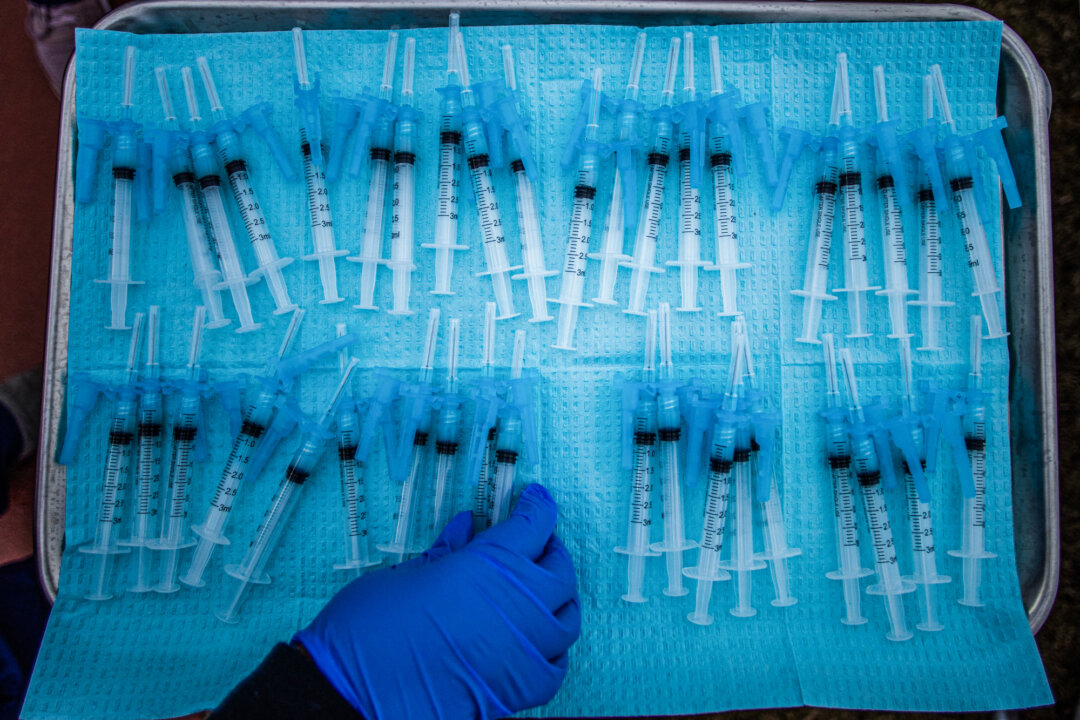 A healthcare worker reaches for COVID-19 vaccines at a vaccination site in Los Angeles on Feb. 16, 2021. (Apu Gomes/AFP via Getty Images)