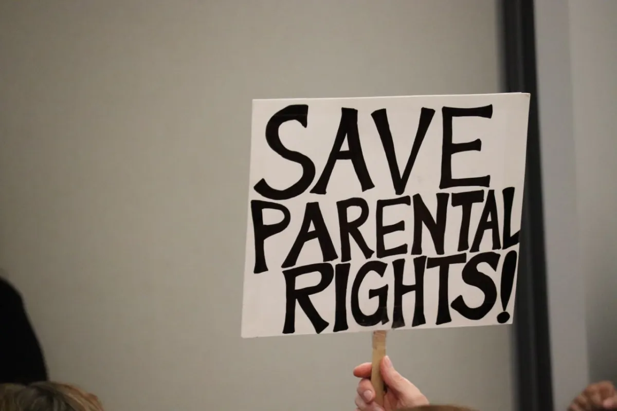 A parental rights advocate raises a sign during an Orange Unified School Board meeting in Orange, Calif., on Sept. 7, 2023. (Mei Lee/The Epoch Times)
