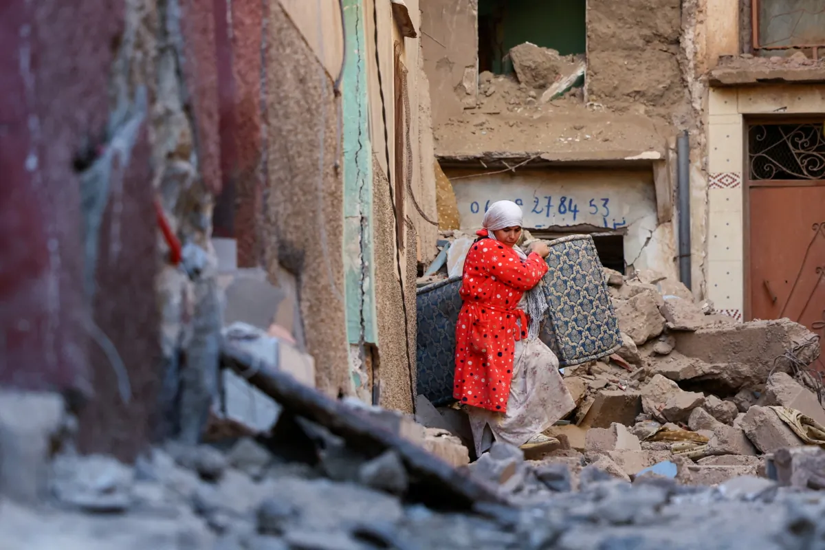 A woman carries belongings out of a damaged building in the aftermath of a deadly earthquake in Moulay Brahim, Morocco, on Sept. 10, 2023. (Hannah McKay/Reuters)