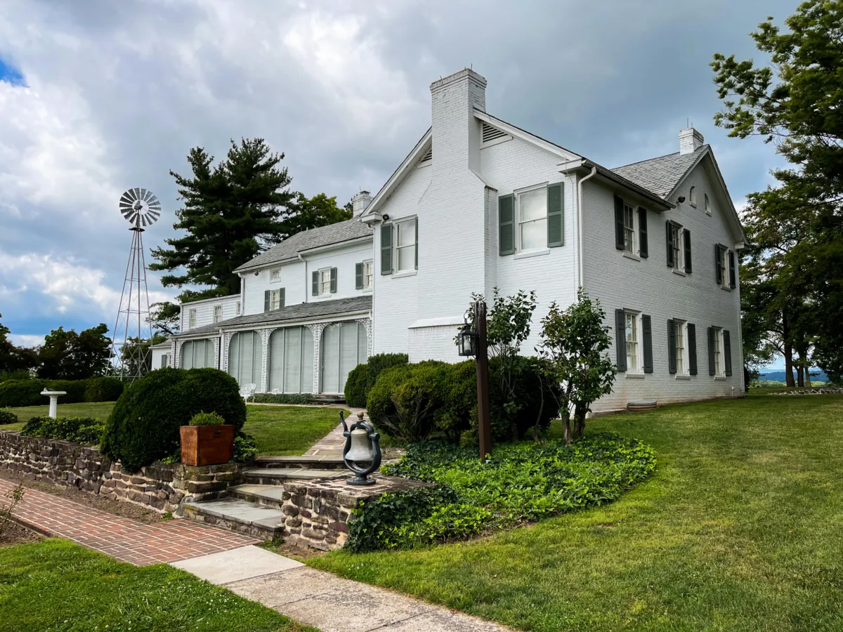 The back view of the Eisenhower farmhouse overlooking a flagpole with a five-star flag, signifying his military rank, and a putting green. (Lynn Topel)