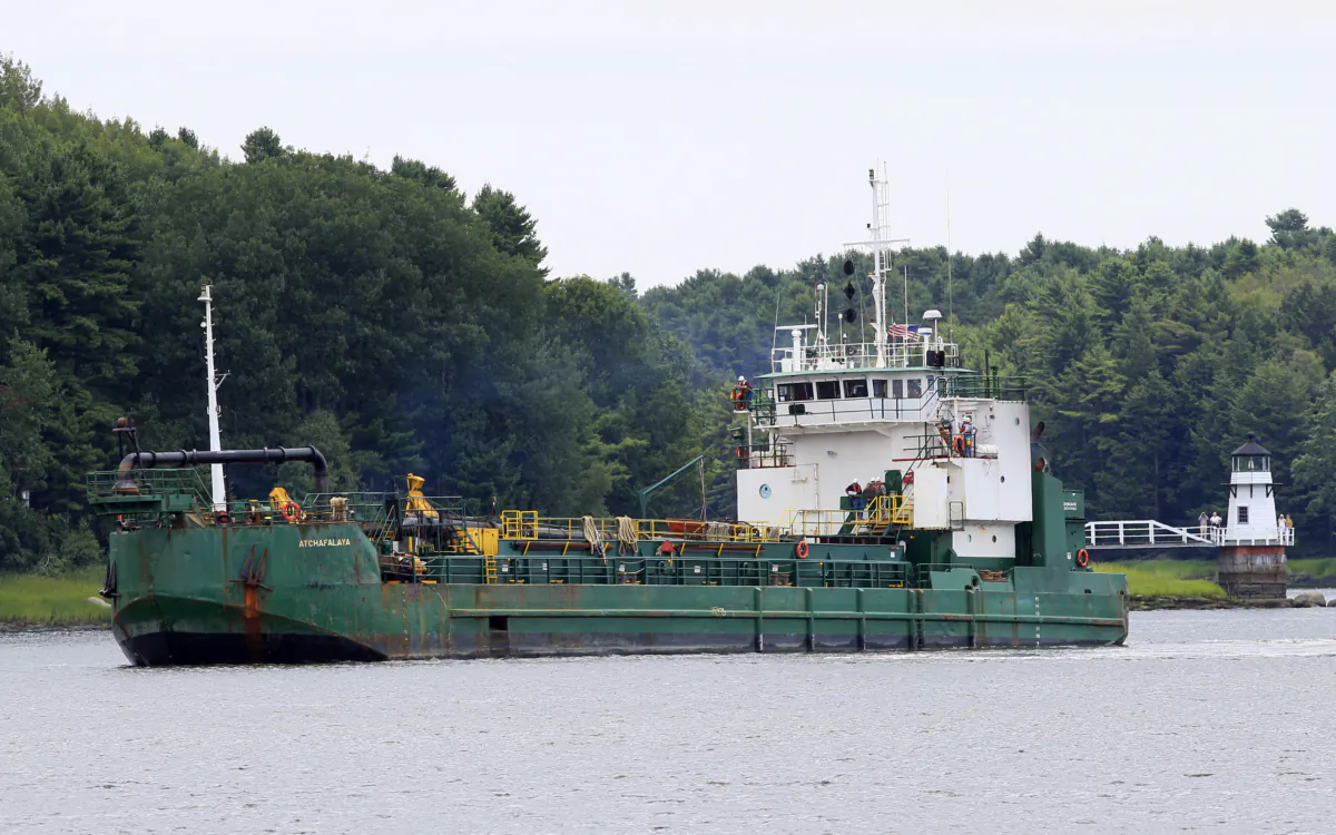 Spectators watch as a dredger works to deepen a shallow channel in the Kennebec River, upstream from the Doubling Point Lighthouse in Arrowsic, Maine, on Aug. 5, 2011. (Robert F. Bukaty/AP Photo)