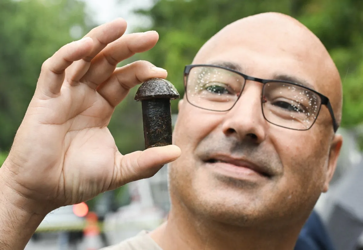 Jeff Harris holds up a rivet from the old Champlain Bridge during a giveaway event in Montreal, Sept. 10, 2023. (The Canadian Press/Graham Hughes)
