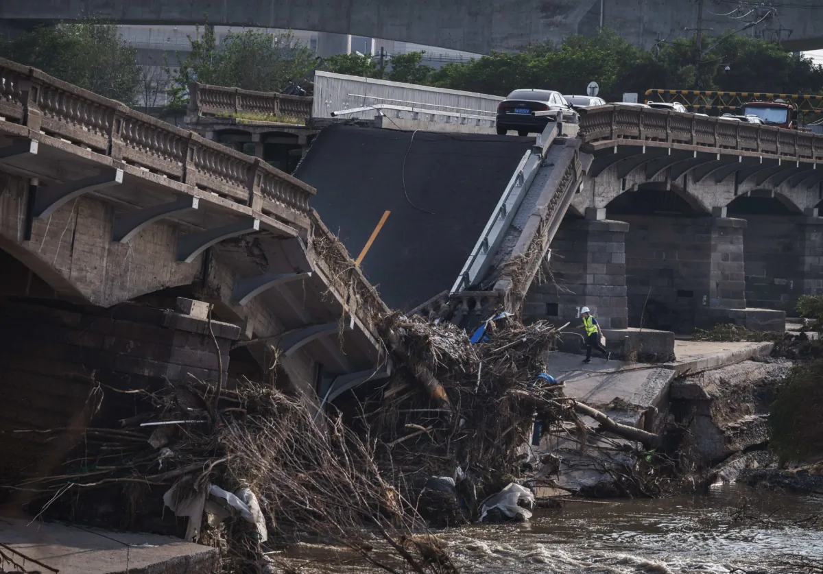 Abandoned cars are seen as a worker inspects a bridge that collapsed after a flash flood caused by heavy rainfall in Beijing, China, on Aug. 4, 2023. (Kevin Frayer/Getty Images)