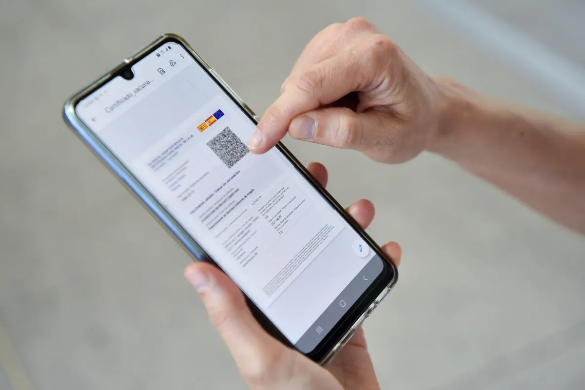 A woman checks her EU Digital COVID certificate on her mobilephone at El Prat airport in Barcelona on July 1, 2021. (PAU BARRENA/AFP via Getty Images)