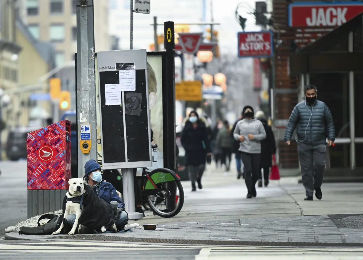 A homeless man sits with his dog on a street in Toronto on Jan. 14, 2021. (The Canadian Press/Nathan Denette)