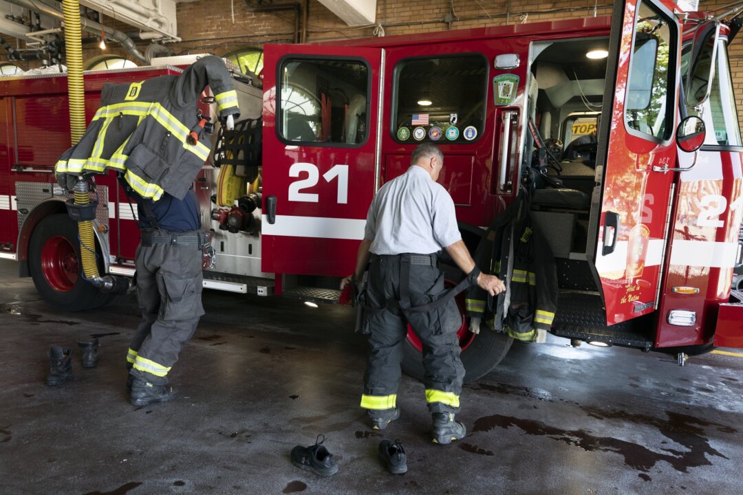 Firefighter Rod MacKinnon (L) and Lt. Chris Stevens don their turnout gear as they respond to a call at the Engine 21 fire station in the Dorchester neighborhood of Boston on Aug. 24, 2023. (Michael Dwyer/AP Photo)