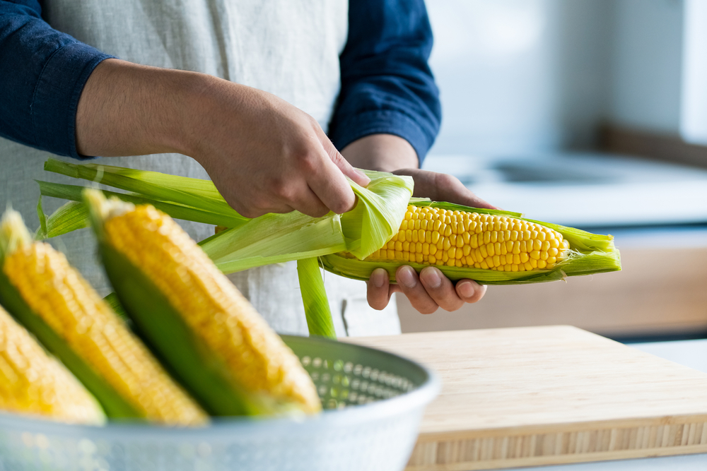 Man Peeling Corn Husk At Kitchen