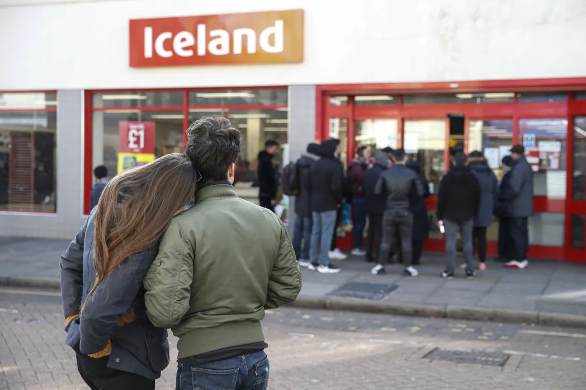 People line up outside an Iceland supermarket on Roman Road in Bow, London, on March 21, 2020. (Hollie Adams/Getty Images)