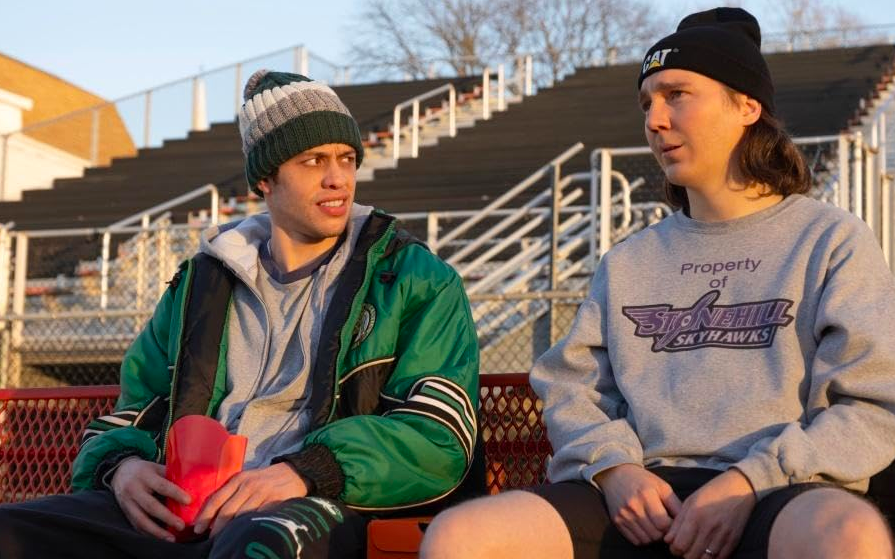two men seat in bleachers in DUMB MONEY
