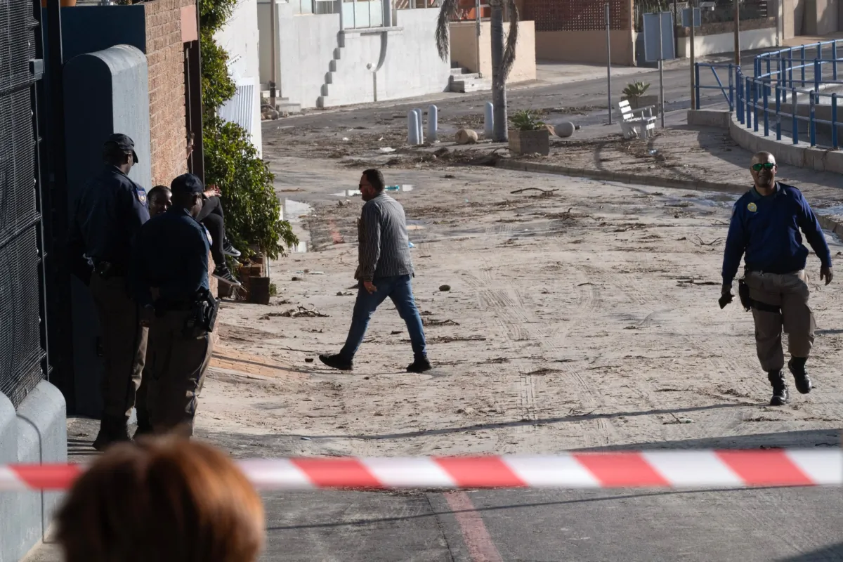 South African law enforcement officers walk across a street strewn with debris after unusually large waves hit the coastal village of Gordon's Bay in South Africa on Sept. 17, 2023, following the spring high tide in the Western Cape Province. (Rodger Bosch/AFP via Getty Images)