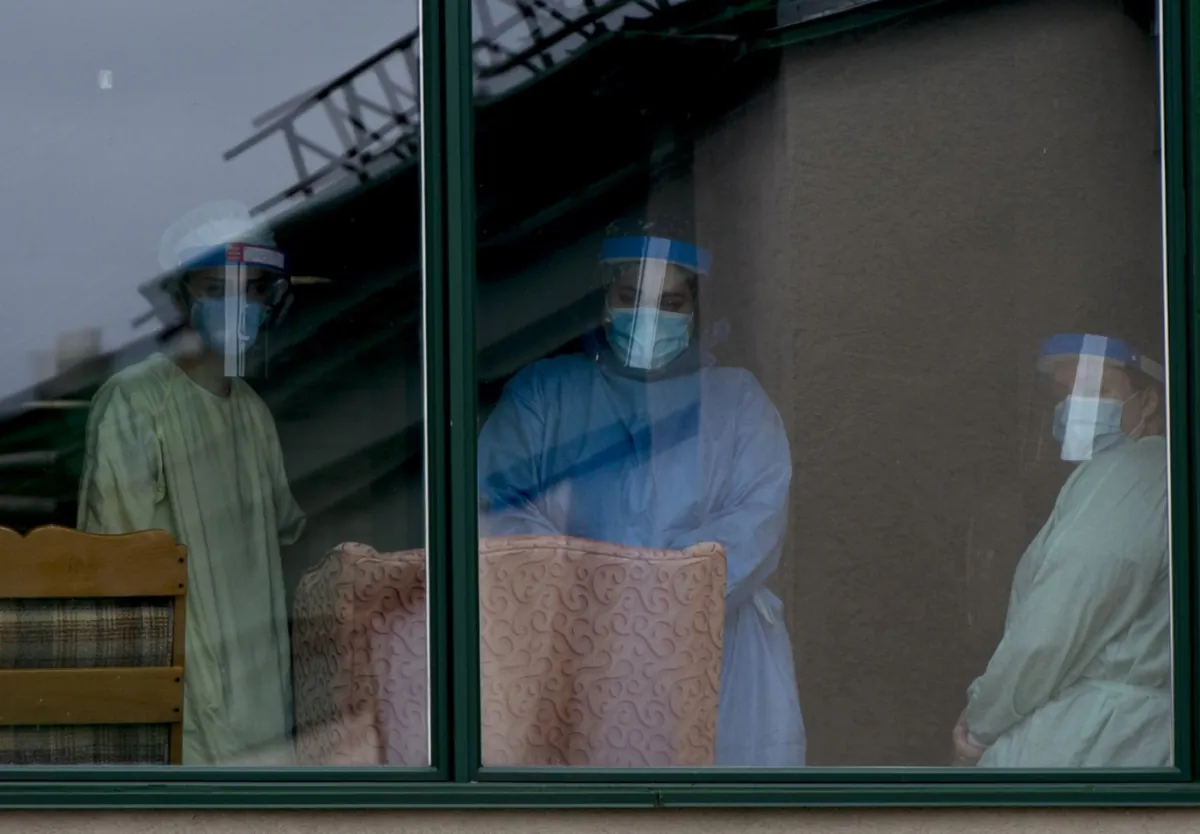 Health-care workers look out from a long-term care home in the Montreal suburb of Dorval, Que., on April 11, 2020. (The Canadian Press/Graham Hughes)