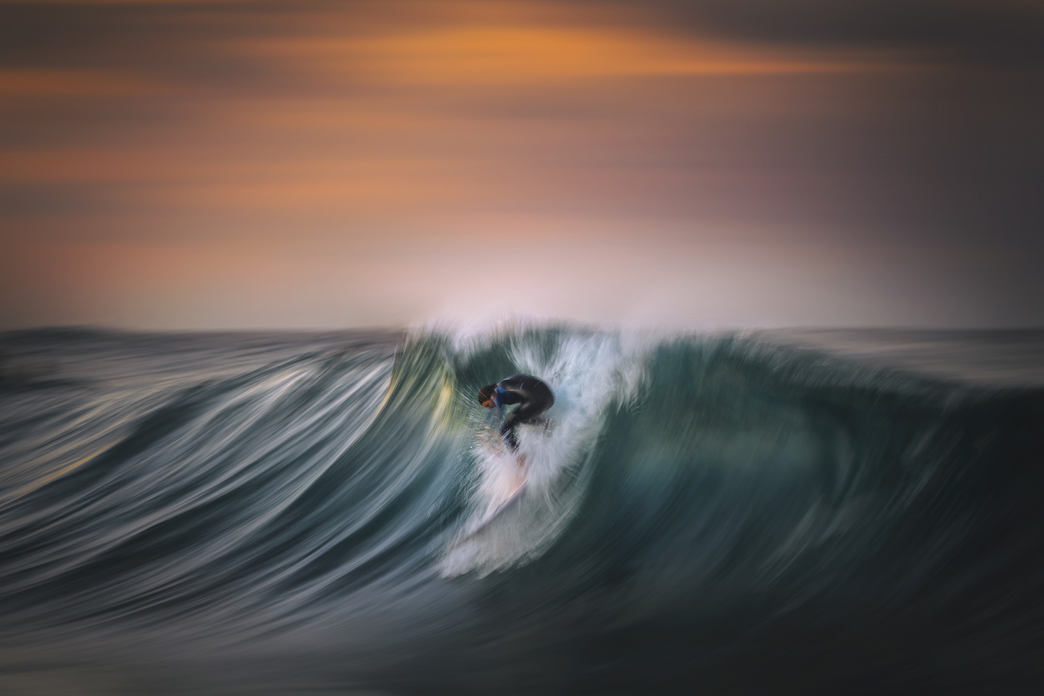Gergo Rugli shoots a surfer braves a big swell, while the setting sun paints the sky red in Sydney, Australia.