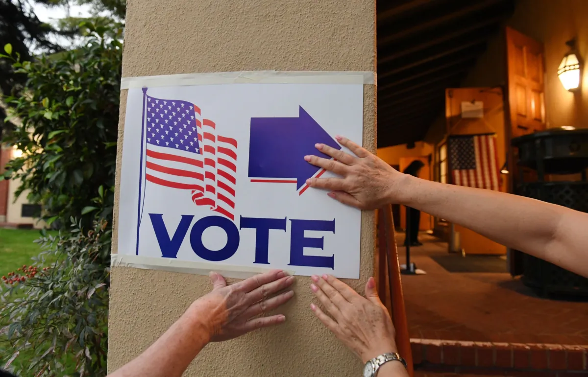 Poll workers attach a sign as they set up a voting station at Laguna Beach City Hall in Laguna Beach in Orange County California, before the polls open, on Nov. 6, 2018. (Robyn Beck/AFP via Getty Images)