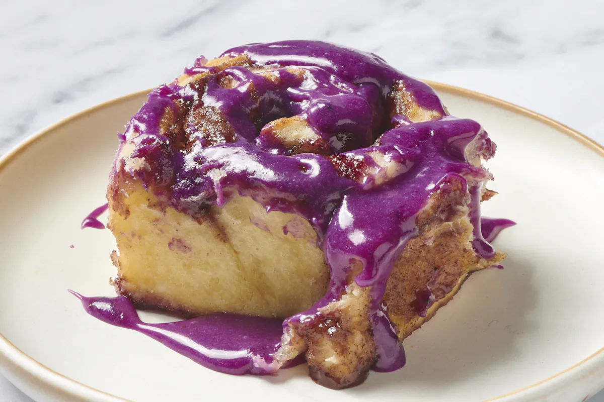 These stunning rolls feature a soft, yeasted dough, warm brown sugar filling with a layer of blueberry sauce, and a drizzle of blueberry cream cheese glaze. (Tribune News Service)
