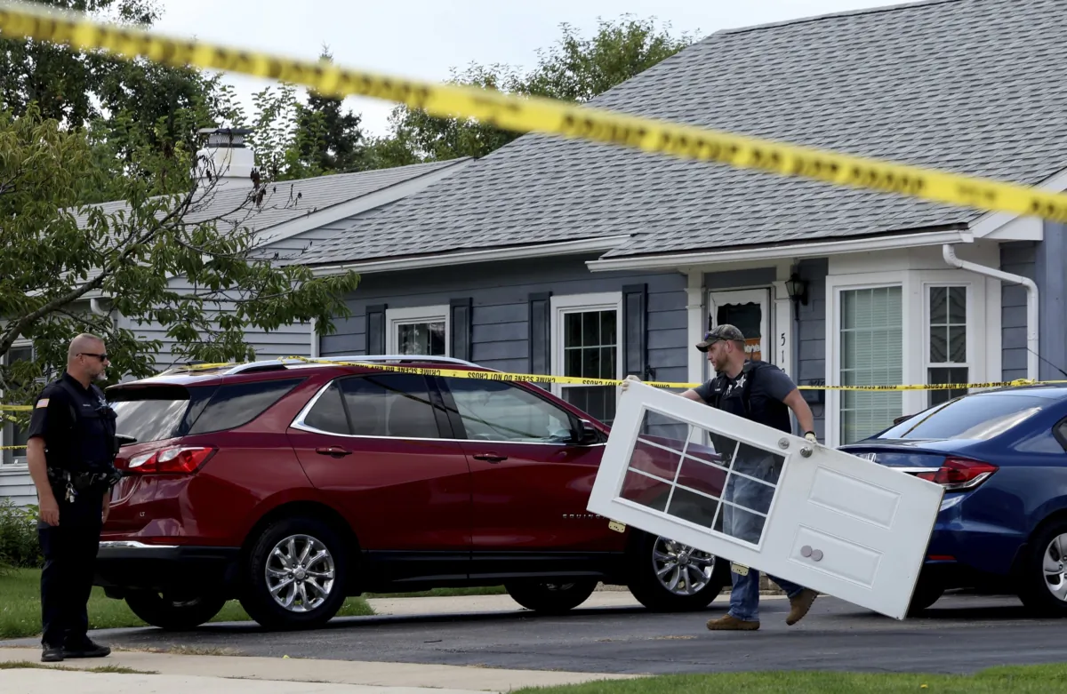 A Romeoville Police officer carries out a door from inside of the home where four people were shot to death in Romeoville, Ill., on Sept. 18, 2023. (Stacey Wescott/Chicago Tribune via AP)
