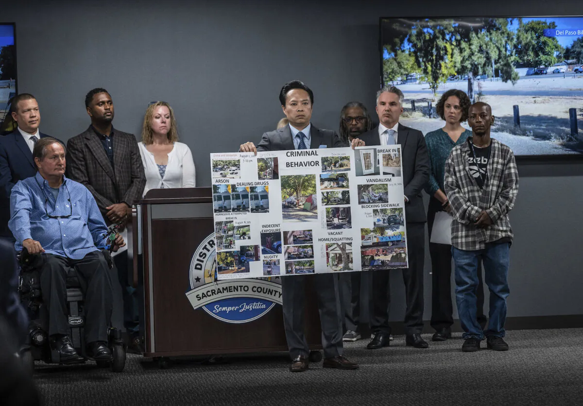 Sacramento County District Attorney Thien Ho holds a poster collage titled "criminal behavior" as he announces that his office is suing the City of Sacramento, Calif., for creating a public nuisance by failing to take stronger action on homeless camps, on Sept. 19, 2023. (Hector Amezcua/The Sacramento Bee via AP)