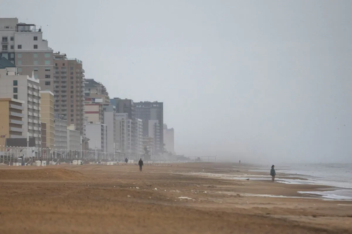 Beach-goers brave the weather and walk along the sand at the Virginia Beach Oceanfront on Sept. 22, 2023, as Tropical Storm Ophelia approaches in Virginia Beach, Va. (Kendall Warner/The Virginian-Pilot via AP)