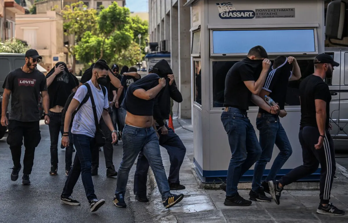 Soccer fans, most of them from Croatia, cover their faces while leaving the Athens Police Headquarters in Athens, on Aug. 11, 2023, as they are being detained as part of the inquiry on the death of a Greek fan during violent clashes. (Angelos Tzortzinis/AFP via Getty Images)