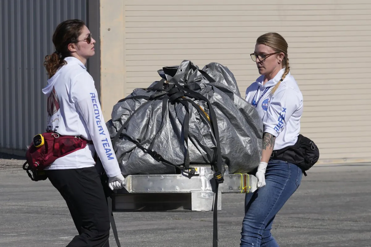 Recovery team members carry a capsule containing NASA's first asteroid samples to a temporary clean room at Dugway Proving Ground in Utah on Sept. 24, 2023. (Rick Bowmer/Pool via AP Photo)