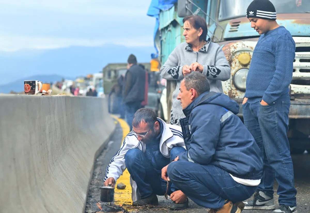 Refugees from Nagorno-Karabakh, a region inhabited by ethnic Armenians, make a drink on a roadside as their vehicles queue on the road leading towards the Armenian border, on Sept. 26, 2023. (David Ghahramanyan/Reuters)